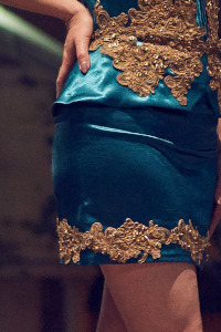 Portion of a teal dress showing fabric and golden embroidery detail